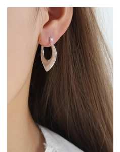 Close-up detail of silver geometric U-shaped earrings with a polished mirror finish on model