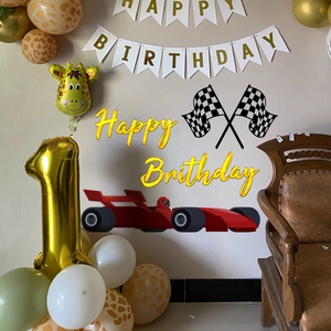 Race car theme birthday party decor with golden flags, giraffe balloons and wall stickers