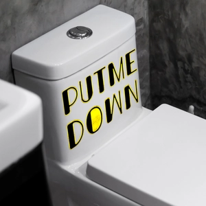 Detail of waterproof Put Me Down sticker on toilet tank with bold black and yellow design