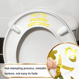 Macro shot of gold foil 'Put Me Down' toilet lid sticker with metallic finish