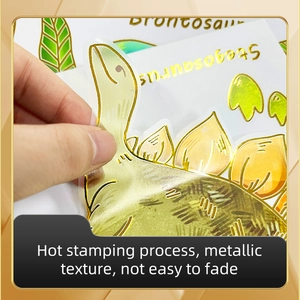 Close-up of gold stamped dinosaur stickers showing transparent texture and metallic finish