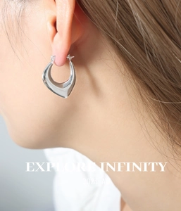 Close-up of a model wearing a chunky silver U-shaped hoop earring with a mirror finish