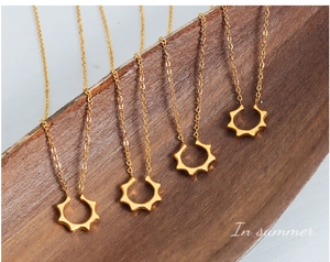 Détail de pendentifs solaires géométriques dorés en forme de U sur de fines chaînes