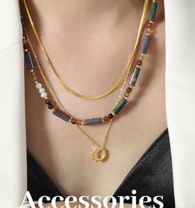Gros plan sur collier doré multicouche avec chaîne serpent, perles et pendentif soleil