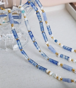Gros plan d'un collier en perles d'eau douce avec calcédoine bleue et perles dorées