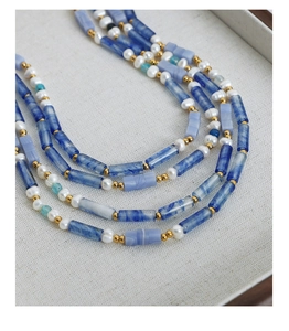 Détail de perles d'eau douce et calcédoine bleue sur un collier en acier doré