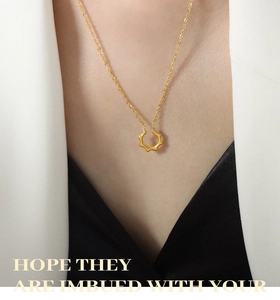 Élégant collier à pendentif octogonal doré porté par un mannequin en blazer blanc