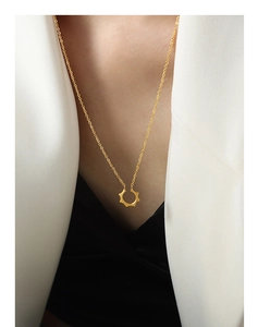 Gros plan d'un collier géométrique en acier titane doré en forme de soleil sur mannequin