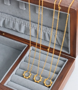 Détail de trois colliers octogonaux dorés avec pendentifs soleil dans un écrin à bijoux