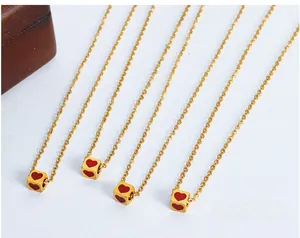 Detail of gold square pendants with red heart enamel on delicate steel chain necklaces
