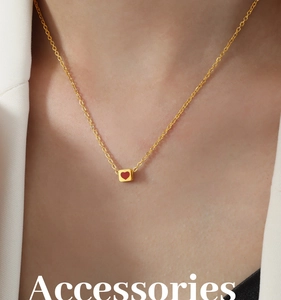 Close-up of a gold chain necklace with a red heart cube pendant on a female model