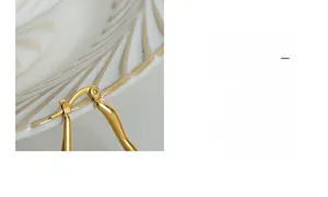 Nahaufnahme goldener geometrischer Ohrringe mit polierter Oberfläche auf einem Keramiktablett