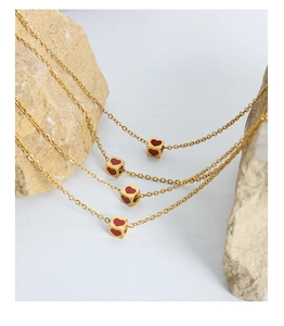 Detailed view of gold square dice pendants with red heart patterns on fine chains