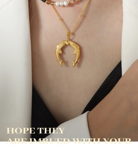 Gros plan d'un collier pendentif queue de poisson doré superposé à des perles de cou