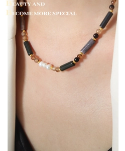 Détail d'un collier vintage avec perles d'eau douce et pierres naturelles brunes sur modèle