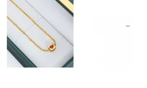 Close-up of golden cube pendant necklace with red heart inlay on soft jewelry box padding