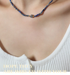 Detail of blue stone beaded necklace with a centered grey labradorite and gold accents