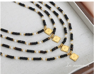 Detail of four bohemian beaded necklaces with heart-embossed gold pendants on grey fabric