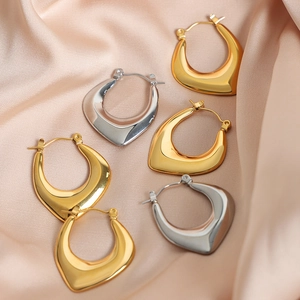 Elegant gold and silver U-shaped hoop earrings on luxury champagne silk fabric