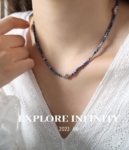 Detail of beaded necklace with blue stones and grey labradorite drop pendant on lace