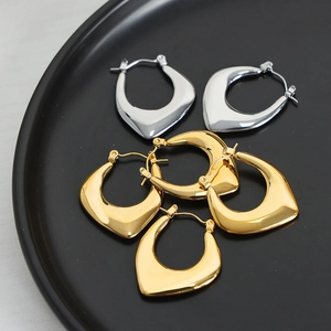Minimalist U-shaped gold and silver earrings with polished finish on black tray