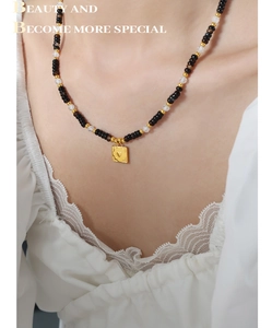 Tiger eye and onyx beaded necklace featuring a golden heart pendant worn by a model