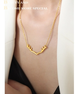 Détail d'un collier pendentif bois de cerf doré porté par un mannequin en veste