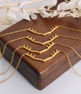 Détail de quatre colliers en titane doré avec pendentifs bois de cerf sur boîte en bois