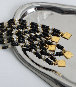 Close-up of black beads and gold heart pendant on a silver metal tray detail