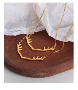 Détail du collier pendentif bois de cerf doré posé sur un plateau en bois et papier blanc