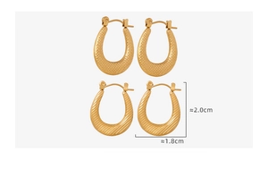 Detail of gold U-shaped earrings featuring textured hammered and ribbed metal finishes