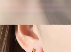 Close-up of a minimalist gold geometric U-shaped earring worn on a model's earlobe