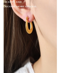 Close-up of gold U-shaped earrings with textured matte finish on a female model