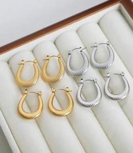 Macro view of four pairs of U-shaped gold and silver textured geometric earrings