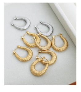 Macro detail of U-shaped earrings featuring textured vintage granulated metal patterns