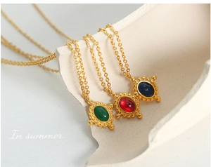 Gros plan de pendentifs croix vintage avec agates rouges, vertes et bleues sur chaînes