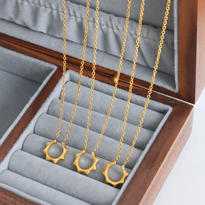 Trois colliers dorés avec pendentif soleil géométrique dans un écrin à bijoux en velours