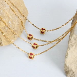 Elegant gold titanium steel necklace featuring a geometric cube pendant with red enamel hearts