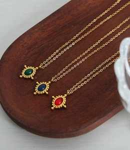 Détail de pendentifs vintage en agate rouge, verte et bleue sur chaînes dorées fines