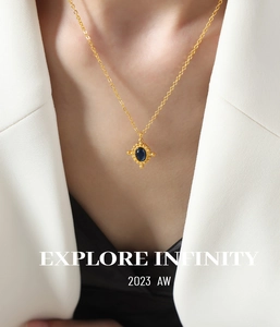 Collier élégant en or avec pendentif en agate bleue porté par un mannequin en blazer blanc