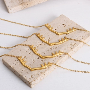 Colliers pendentifs bois de cerf dorés sur présentoir en pierre au style minimaliste