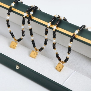 Bohemian black onyx beaded necklace with a gold heart relief square pendant on a jewelry box