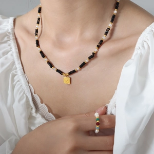 Elegant beaded tiger eye and onyx necklace with gold square heart pendant on model