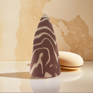 Cone-shaped marble makeup sponge with storage case on marble and mirror platform