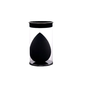 Black teardrop makeup sponge in a transparent cylindrical storage case on white background