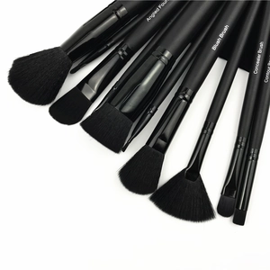 Close-up of 11-piece black makeup brush set with functional labels on matte wooden handles