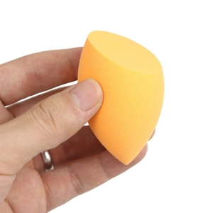 Orange slanted makeup sponge held in hand for applying foundation and concealer
