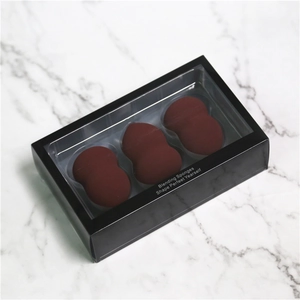 Lot de trois éponges de maquillage rouge bordeaux dans une boîte noire sur marbre