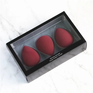 Three burgundy teardrop makeup blending sponges in a black window box on marble