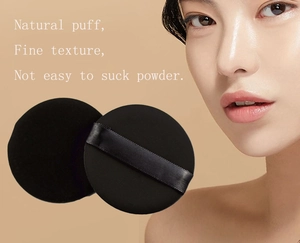 Detail of two black non-latex cosmetic puffs with satin ribbons for smooth base makeup